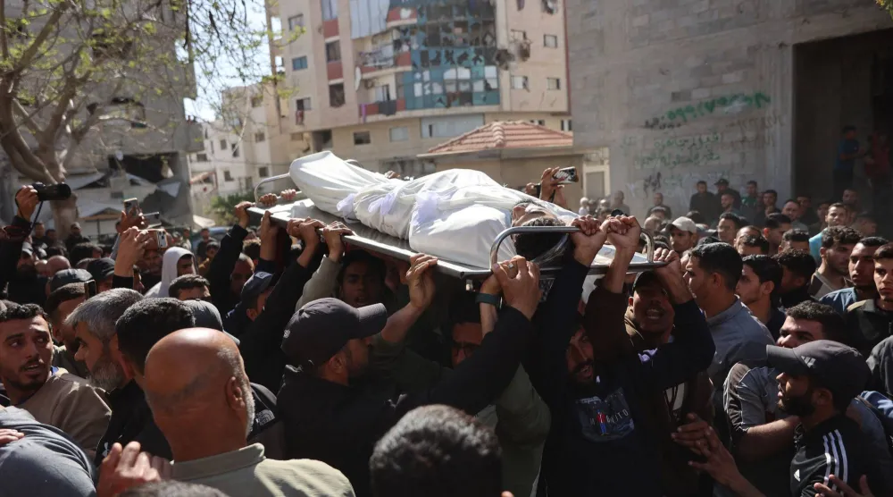 فلسطينيون نازحون يحملون جثماناً خلال جنازة أربعة أشخاص قُتلوا في غارة إسرائيلية استهدفت سيارة بمدينة غزة (أ.ف.ب)