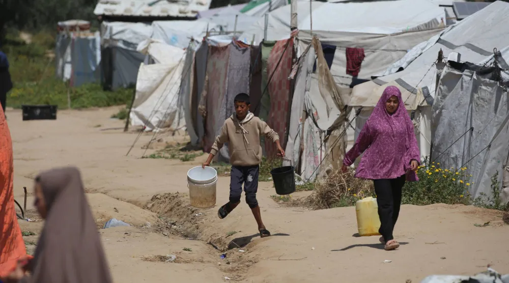 فلسطينيون يسعون للحصول على ماء في مخيم البريج بوسط قطاع غزة (أ.ف.ب)