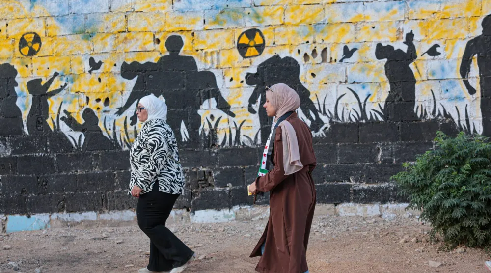 جدارية تُحيي ذكرى الهجوم الكيميائي عام 2013 في زملكا بضواحي دمشق مساء الخميس (إ.ب.أ)