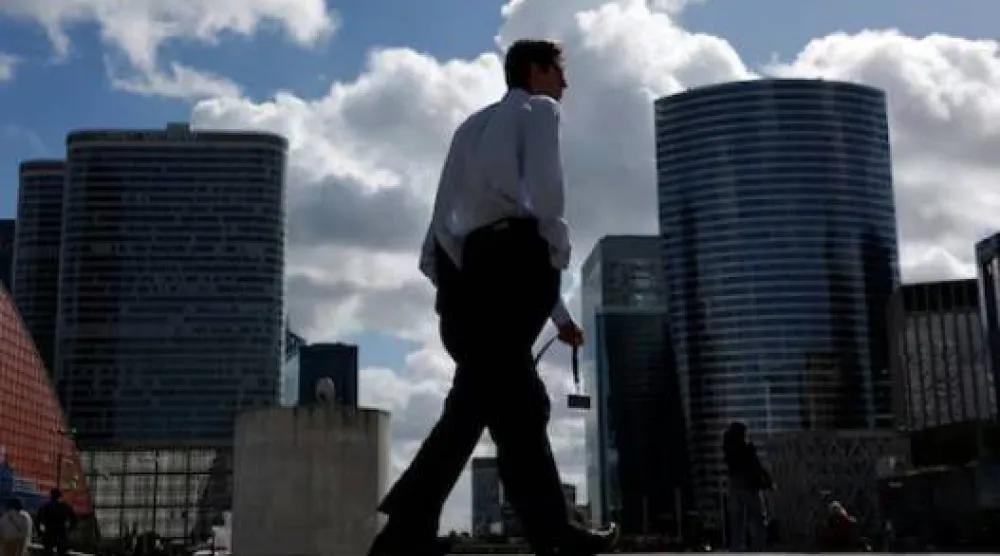 شخص يسير بجوار ناطحات السحاب في الحي المالي والتجاري في بوتو بالقرب من باريس (رويترز)