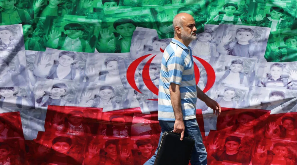 رجل يمرّ أمام عَلم إيران منصوب على جانب الطريق في طهران (أ.ف.ب)