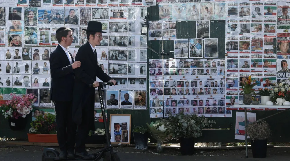 يمرّ أفراد من الجالية اليهودية بسياراتهم أمام جدار تذكاري، مُخصّص لضحايا هجمات 7 أكتوبروذلك في شارع لايمز أفينيو بمنطقة غولدرز غرين (رويترز)