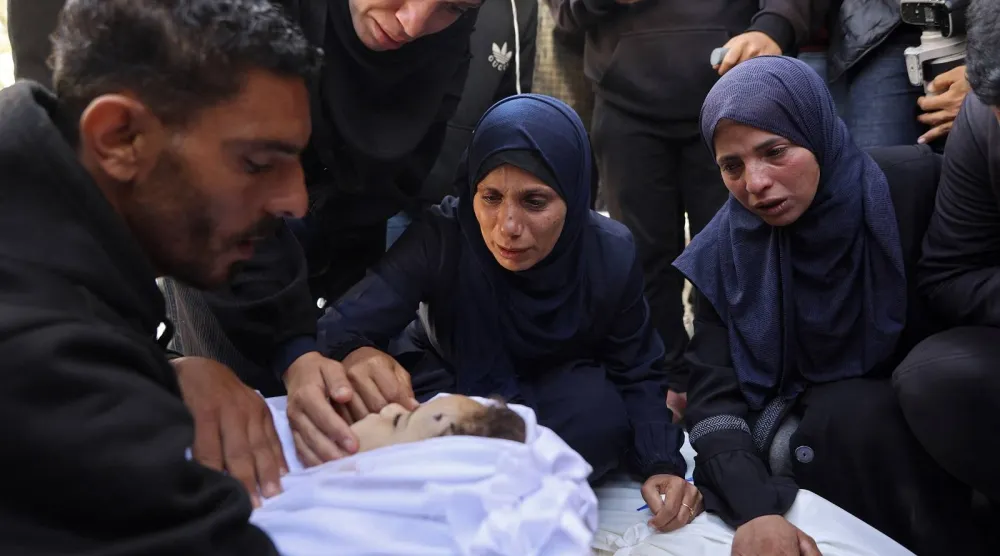 مشيعون يبكون بجوار جثة طفل في مستشفى بمدينة غزة (أ.ف.ب)