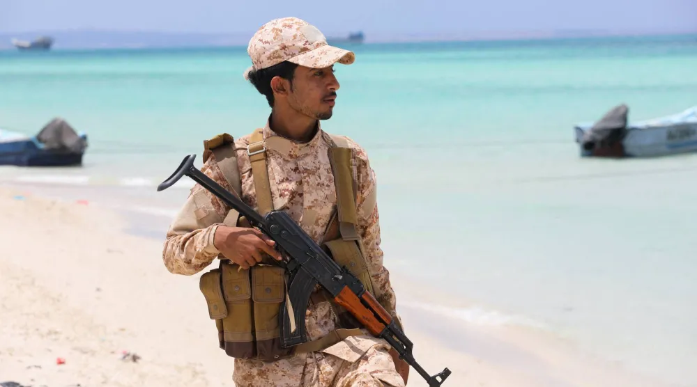 جندي يمني يسير على ساحل باب المندب (رويترز)