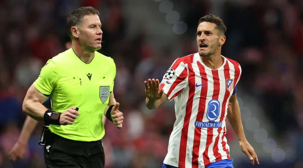 كوكي لاعب أتلتيكو مدريد يتحدث مع الحكم داني ماكيلي قبل مراجعة تقنية الفيديو لاحتمال احتساب ركلة جزاء (رويترز)