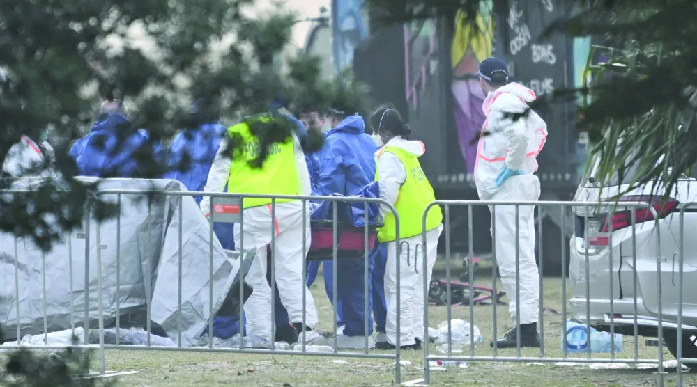 خبراء الأدلة الجنائية خلال معاينة جثة أحد الضحايا بموقع إطلاق النار بشاطئ بونداي في سيدني (أرشيفية - إ.ب.أ)