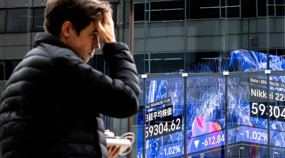 متداول يمر أمام لوحة أسعار إلكترونية في بورصة طوكيو (أ.ف.ب)
