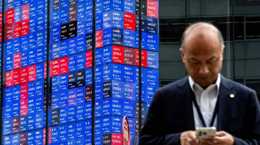 رجل يمر أمام شاشة تعرض حركة الأسهم في وسط العاصمة اليابانية طوكيو (أ.ف.ب)