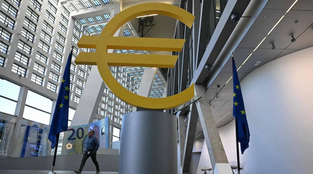 رجل يمر بجانب شعار اليورو بمركز الزوار التابع للبنك المركزي الأوروبي في فرنكفورت (أ.ف.ب)