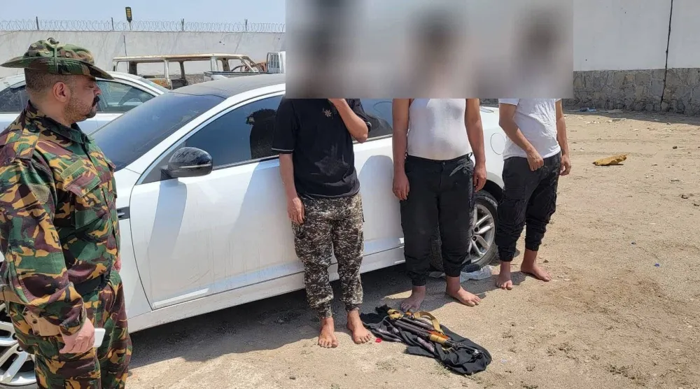 رجل أمن يقف بجوار عدد من أفراد الخلية التي تتهمها أجهزة الأمن اليمنية بالتخطيط لاغتيالات (الحكومة اليمنية)