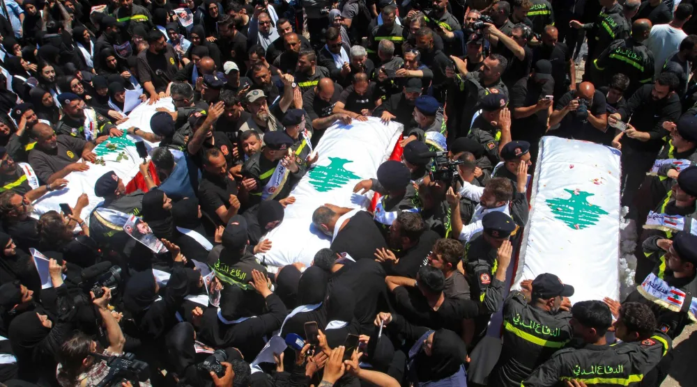 مشيِّعون يشاركون في جنازة 3 عناصر من الدفاع المدني قُتلوا بغارة إسرائيلية في جنوب لبنان (أ.ف.ب)