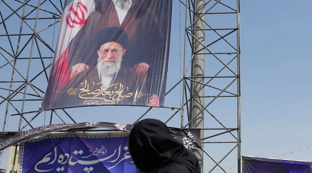 Tahran'da bir kadın, ABD-İsrail saldırılarında öldürülen baba Ali Hamaney ile oğlu Mücteba Hamaney’e ait afişlerin önünden geçiyor (AP)