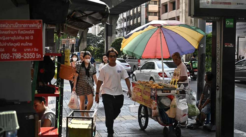 This photo taken on April 30, 2026 shows a street vendor selling fried food along Silom road in Bangkok. (Photo by Lillian SUWANRUMPHA / AFP) 