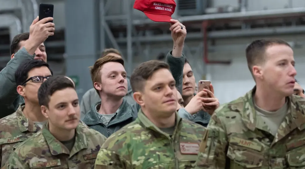 Aralık 2018'de Ramstein Hava Üssü'nde Başkan Trump ve First Lady için düzenlenen resepsiyonda bir Amerikan askeri, MAGA logosunu taşıyan şapkayı havaya kaldırıyor (AFP)
