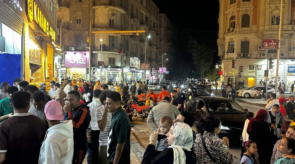 الناس يسيرون في شوارع وسط القاهرة ليلاً (أ.ف.ب)