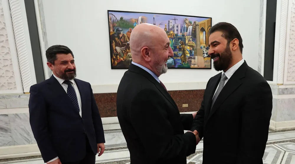 صورة وزعتها الرئاسة العراقية في 27 أبريل 2026 تظهر الرئيس نزار أميدي (وسط) وهو يصافح المكلّف علي الزيدي (يمين) في بغداد