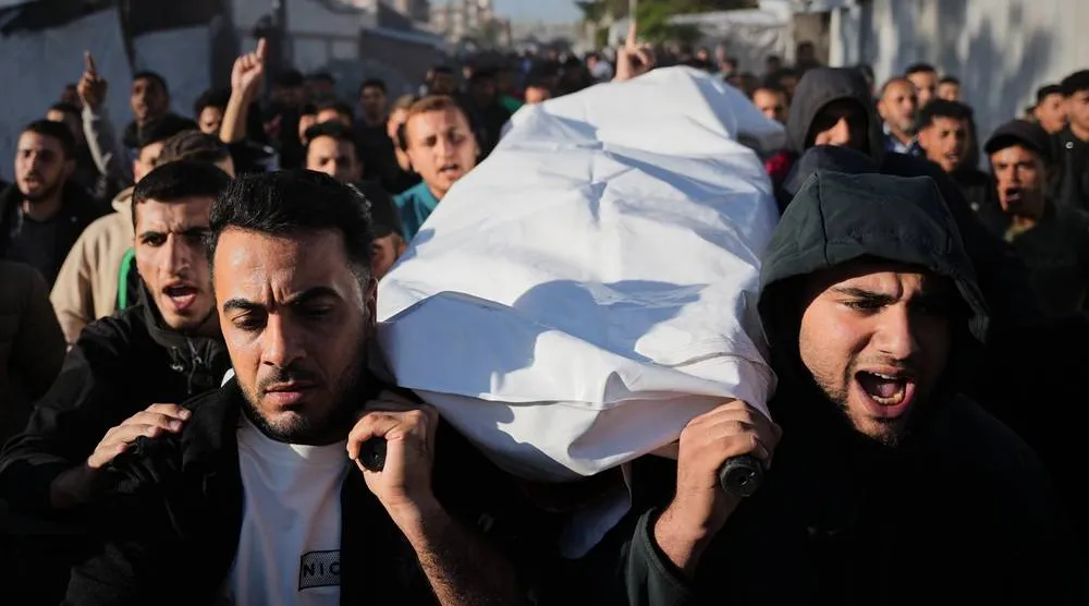 فلسطينيون يحملون جثمان فلسطيني قتل في غارة إسرائيلية (أ.ب)