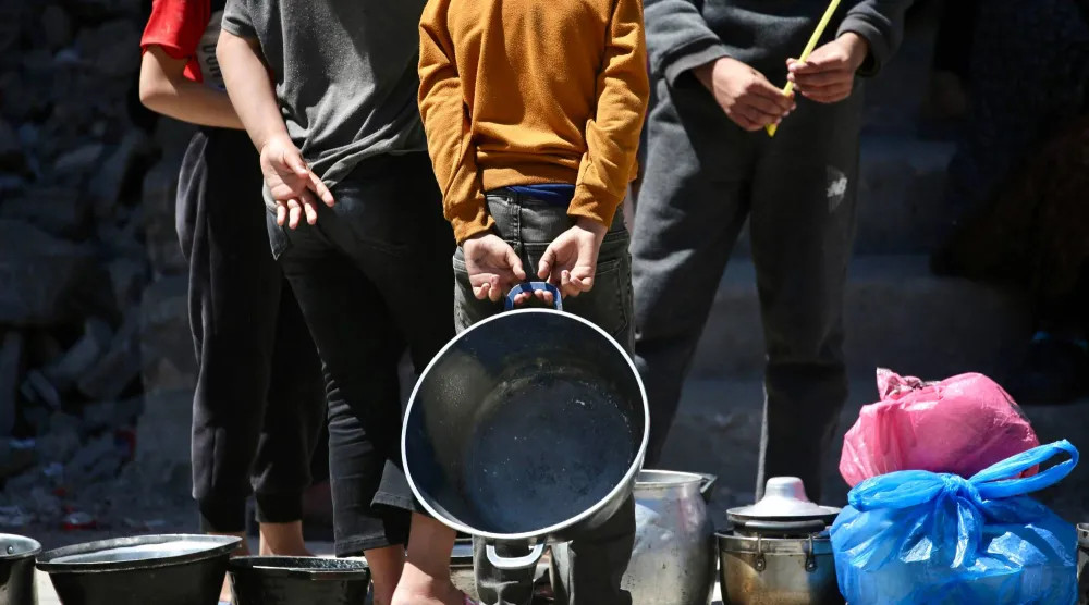 يصطفّ فلسطينيون نازحون لتلقّي حصص غذائية من مطبخ خيري في مخيم البريج للاجئين وسط قطاع غزة (أ.ف.ب)