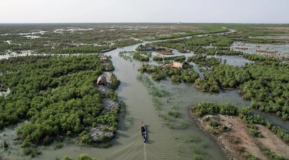 A drone view shows a boat moving through water channels amid vegetation at the Chibayish marshes in Dhi Qar province, Iraq, May 7, 2026. REUTERS/Thaier Al-Sudani