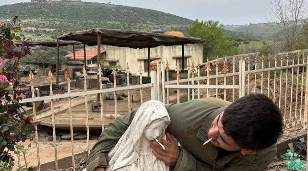 جندي إسرائيلي يضع سيجارة في فم تمثال السيدة العذراء في بلدة دبل بجنوب لبنان (رويترز)