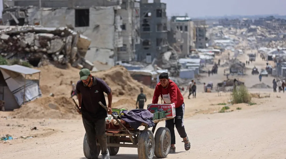 فلسطينيون نازحون ينقلون صناديق في عربة عبر أنقاض المباني المدمرة في جباليا شمال قطاع غزة (أ.ف.ب)