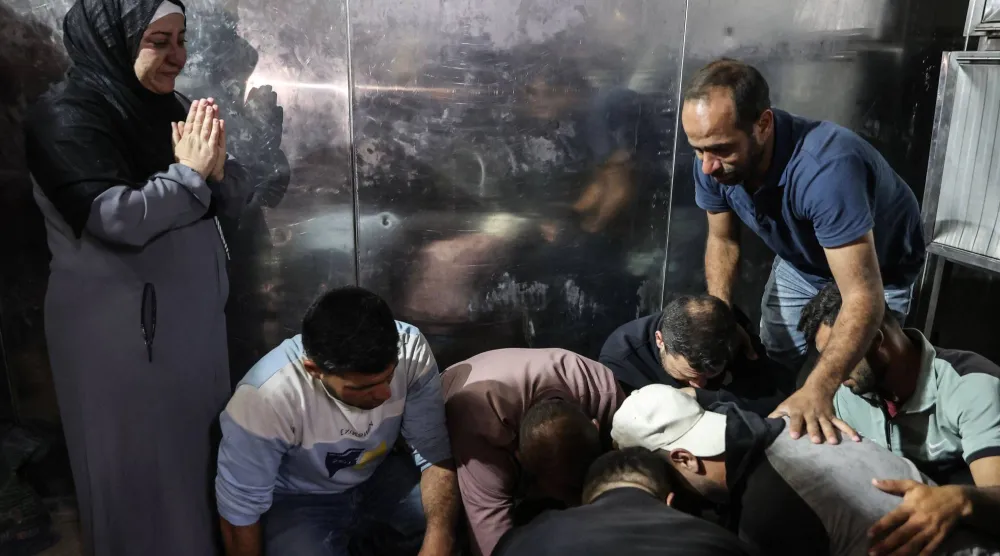 فلسطينيون يبكون ذويهم الذين قُتلوا خلال غارات إسرائيلية في مستشفى الشفاء بمدينة غزة (أ.ف.ب)