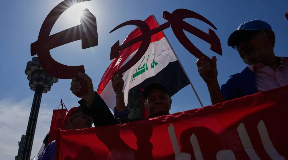 أنصار الحزب الشيوعي العراقي يحملون رمز المطرقة والمنجل خلال مشاركتهم في احتفالات عيد العمال ببغداد يوم الجمعة 1 مايو 2026 (أ.ب)
