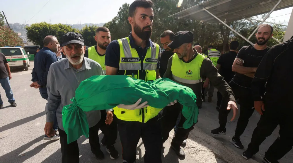 عنصر في الدفاع المدني يحمل الطفلة مريم فحص التي تبلغ 6 أشهر من عمرها والتي قُتلت مع عائلتها في القصف الإسرائيلي الذي استهدف بلدة السكسكية في قضاء صيدا يوم السبت (رويترز)