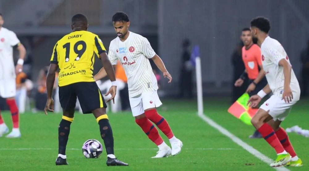 طارق عبدالله يحاول المرور من ديابي لاعب الاتحاد (موقع نادي ضمك)