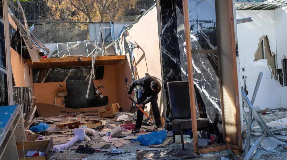 عامل فلسطيني يستخدم مطرقة ثقيلة لهدم متجره قبل وصول فريق هدم تابع للجيش الإسرائيلي في بلدة العيزرية الفلسطينية المحتلة بالضفة الغربية المتاخمة للقدس الشرقية (أ.ف.ب)