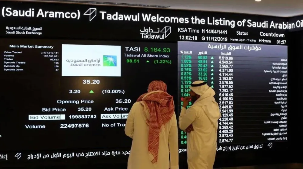مستثمران يتابعان شاشة التداول في «السوق المالية السعودية» (رويترز)
