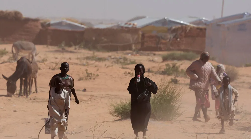 نازحون من دارفور يسيرون وسط عاصفة رملية في مخيم للاجئين السودانيين بشرق تشاد في 30 نوفمبر 2025 (رويترز)