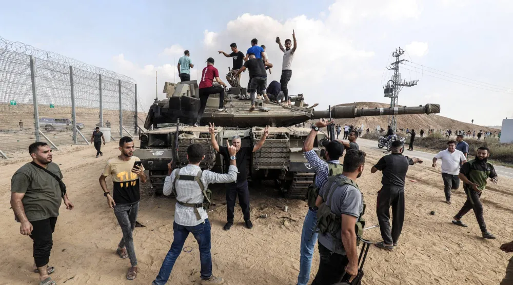 فلسطينيون فوق دبابة إسرائيلية سيطر عليها مقاتلو «كتائب القسام» قرب خان يونس يوم 7 أكتوبر 2023 (د.ب.أ)