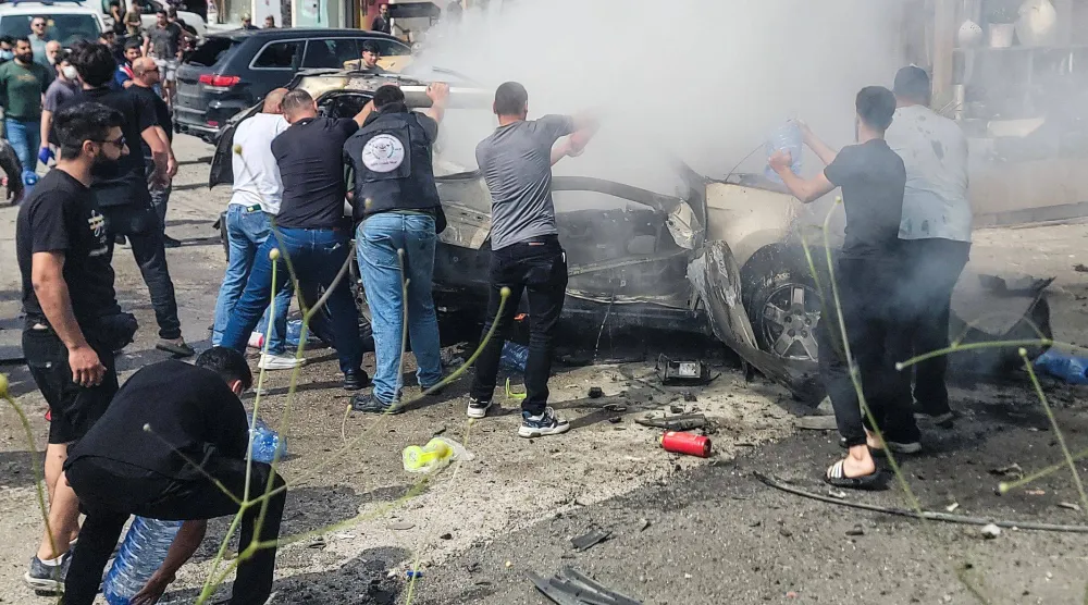 جهود لإطفاء سيارة تحترق بعد غارة نفذتها مسيّرة إسرائيلية في بلدة الجية جنوب بيروت (أ.ف.ب)