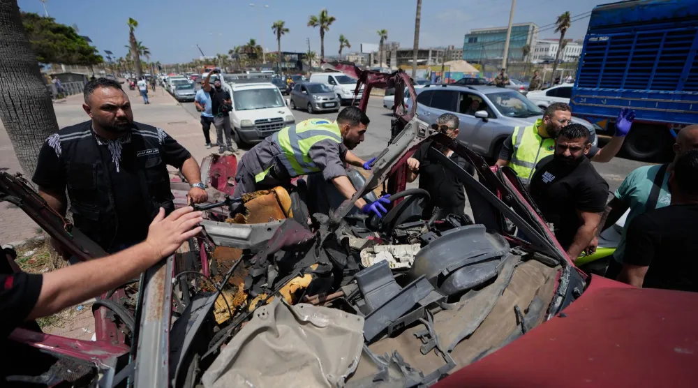 تجمعت قوات الأمن وفرق الإنقاذ حول مركبة متضررة بشدة بعد إصابتها بغارة جوية إسرائيلية في صيدا (أ.ب)