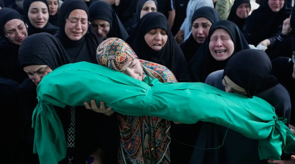 نساء يبكين وهن يحملن جثمان طفلة بالغة من العمر 6 أشهر خلال موكب جنازة لضحايا غارة جوية إسرائيلية وقعت في قرية السكسكية جنوب لبنان (أ.ب)