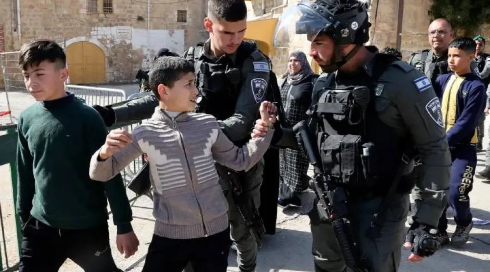 عناصر من الشرطة الإسرائيلية يعتقلون أطفالاً فلسطينيين في الخليل بالضفة الغربية (أ.ف.ب)