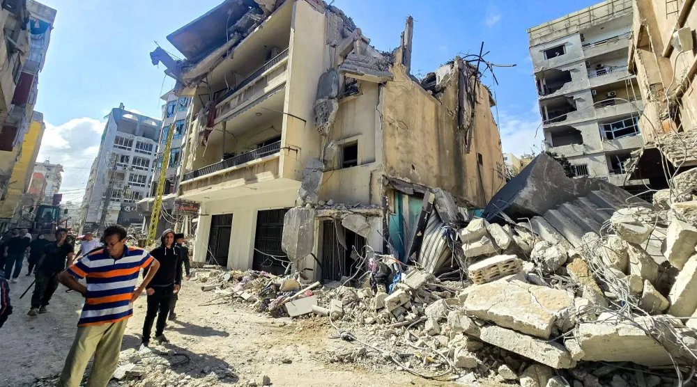 مواطنون يعاينون الدمار الذي طال عدداً من المباني في مدينة صور نتيجة القصف الإسرائيلي (أ.ف.ب)