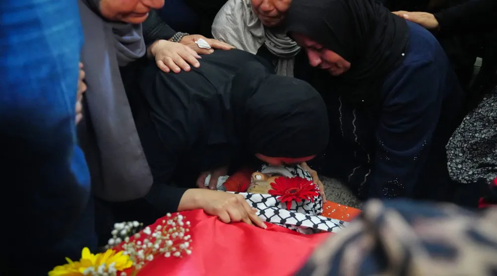 يلقي مشيعون النظرة الأخيرة على جثمان فلسطيني خلال جنازته في بلدة دير قديس بالضفة الغربية (أ.ب)