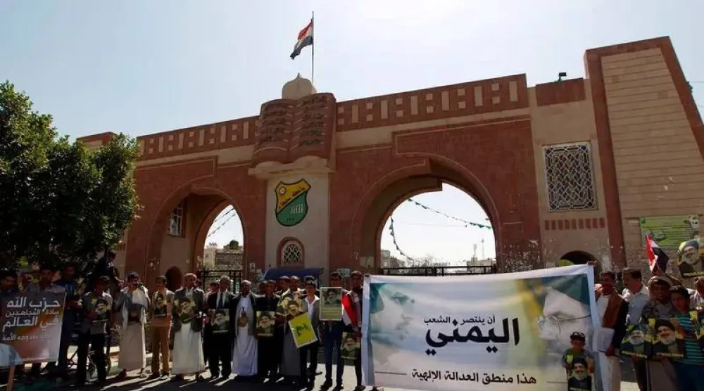 حوثيون أمام بوابة جامعة صنعاء يرفعون صور زعيمهم وزعيم «حزب الله» اللبناني الأسبق نصر الله (أرشيفية - أ.ف.ب)