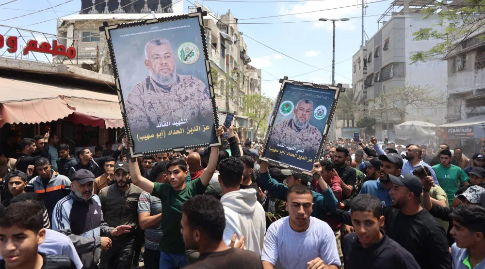فلسطينيون يحملون صور عز الدين الحداد خلال تشييعه في مدينة غزة السبت (أ.ف.ب)