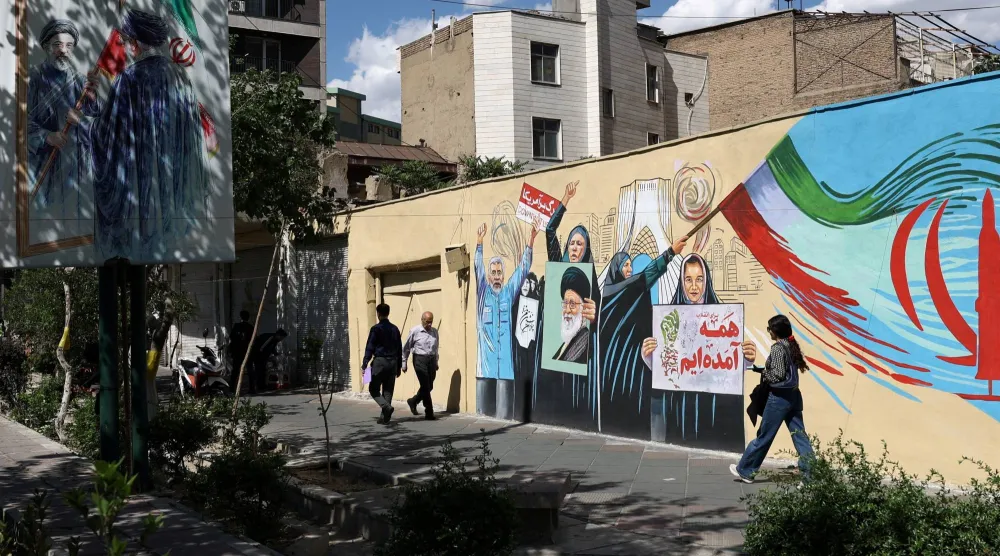 أشخاص يسيرون بجانب جدارية جدارية تحمل صورة المرشد الايراني السابق علي خامنئي في أحد شوارع طهران (رويترز)