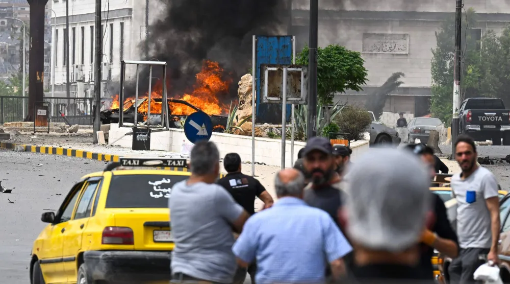 مدنيون يتابعون احتراق سيارة في موقع التفجير بدمشق الثلاثاء (أ.ف.ب)