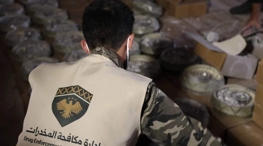 موظف في «إدارة مكافحة المخدرات» في سوريا يفحص صناديق تهريب شحنة الكبتاغون (الداخلية السورية)