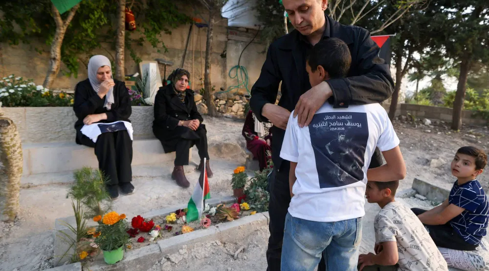 الفلسطيني سامح اشتية والد يوسف سامح اشتية البالغ من العمر 15 عاماً الذي قُتل في 23 أبريل على يد جنود إسرائيليين في مدينة نابلس يعانق ابنه في أثناء زيارتهما لقبر ابنه يوسف في مقبرة قرية تل غرب نابلس في الضفة الغربية المحتلة 12 مايو 2026 (أ.ف.ب)

