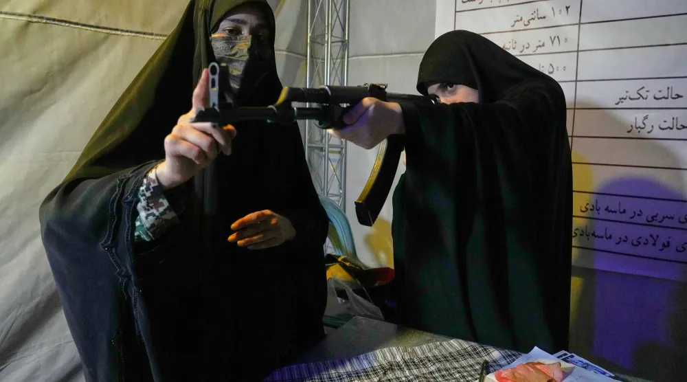 متطوعة في قوة «الباسيج» التابعة لـ«الحرس الثوري» (على اليسار) تقدّم تعليمات حول كيفية التعامل مع بندقية كلاشينكوف خلال تدريب على استخدام الأسلحة في طهران يوم 19 مايو 2026 (أ.ب)