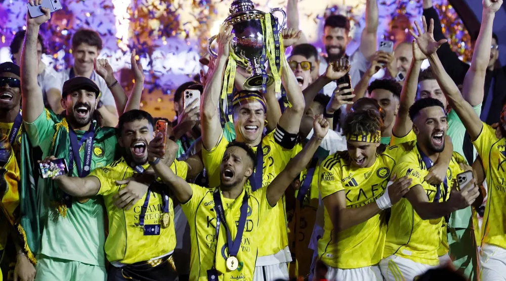 رونالدو يرفع كأس الدوري السعودي عاليا (رويترز)