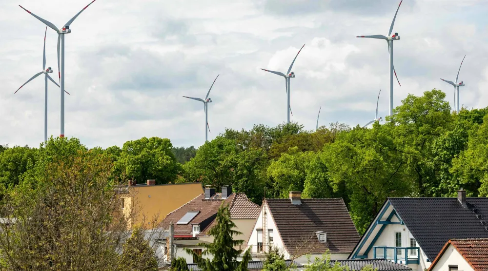 Conventional wind turbines are seen behind houses in Schipkau, eastern Germany on May 13, 2026. (Photo by Odd ANDERSEN / AFP) 
