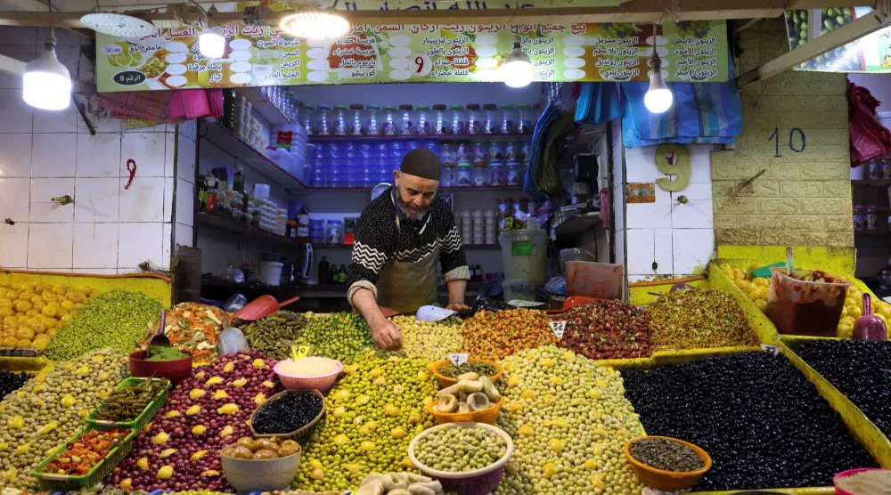صاحب متجر يرتب الزيتون داخل سوق شعبية في الدار البيضاء (رويترز)