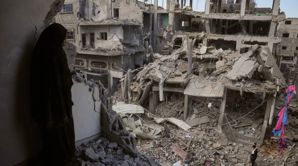 فلسطينيان يعاينان ركام مبنى بعد استهدافه بغارة إسرائيلية في مخيم المغازي للاجئين وسط قطاع غزة الخميس (أ.ب)